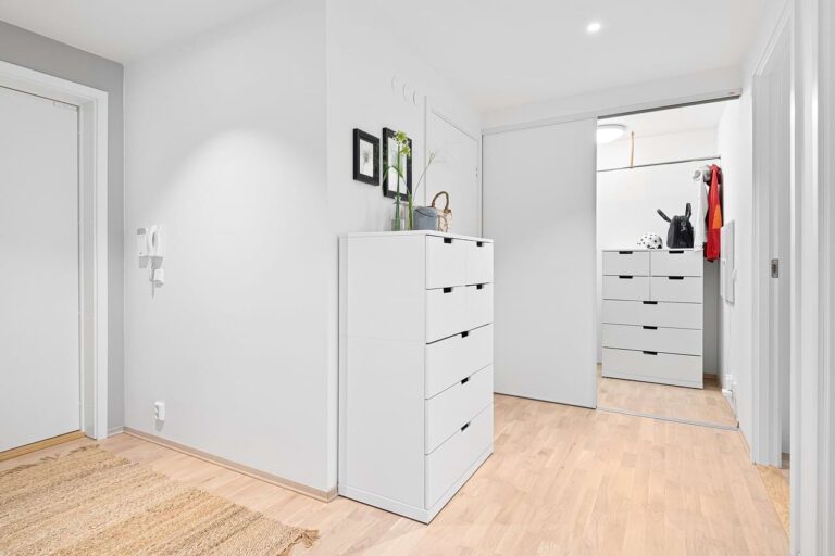 Minimalist hallway with white dressers and wooden floor.